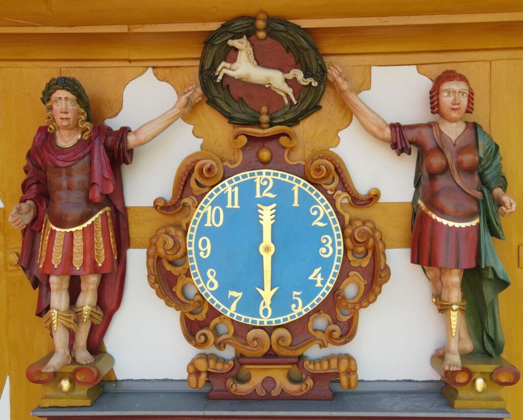 Uhr mit seitlichen Figuren und Ross